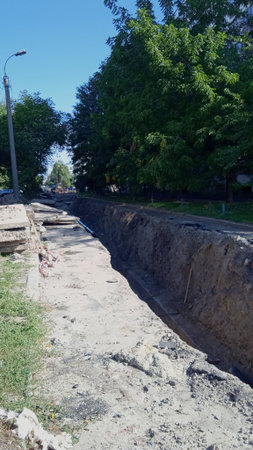 Part of the road is dug up, there are old concrete slabs on the side, and the worn-out water pipe is being replaced.の写真素材
