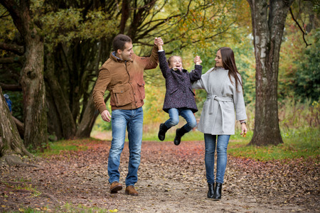 Lovely family walking in the autumn forest. Happy parents enjoying fresh air and beautiful nature, holding hands, talking, smiling and laughing. Healthy lifestyleの写真素材