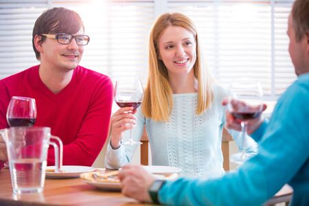 Group Of Young People Enjoying Meal and drinking wine In Restaurant. Friends Dining, celebrating and Hanging out. Hands toasting.の写真素材