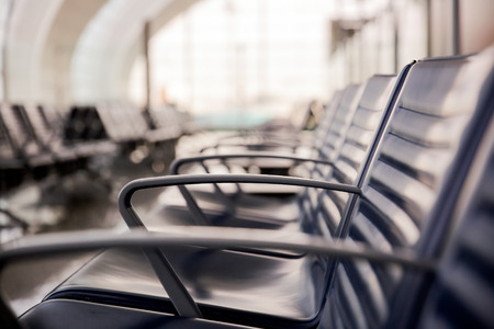 Row of empty leather chairs in the departure lounge at the airport. International airport terminal and the window background.の写真素材