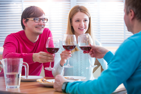Group Of Young People Enjoying Meal and drinking wine In Restaurant. Friends Dining, celebrating and Hanging out. Hands toasting.の写真素材