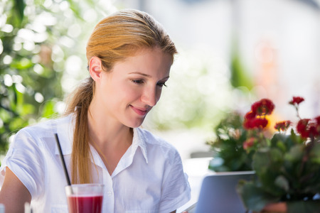 Young business woman talking on smartphone and working at the laptop. Drinking cocktail outdoors cafe in City with Happy smile. Healthy lifestyle.の写真素材