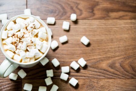 White cup of hot chocolate with marshmallows and cinnamon on dark wooden background. Flat lay. Top viewの写真素材