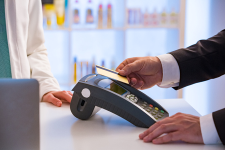 Customer paying with contactless card. NFC technology payment in store. Close Up. Shopping in pharmacy.の写真素材