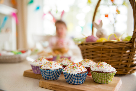 Easter celebration, close-up table with glazed cupcakes, basket with Easter eggs and bunny. Happy family holidayの写真素材
