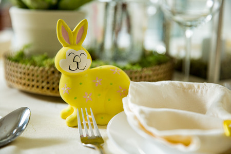 Beautiful served round table with decorations in dining room. Little yellow bunny, willow branches decorated with colorful Easter eggs. Spring holiday setting. Close-upの写真素材