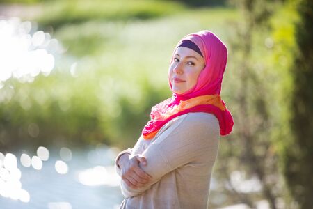 Attractive confident woman in hijab standing outdoors in sunny summer day, happily smiling. Muslim woman lifestyle conceptの写真素材