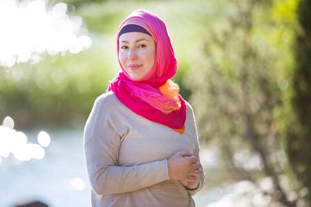 Attractive confident woman in hijab standing outdoors in sunny summer day, happily smiling. Muslim woman lifestyle conceptの写真素材