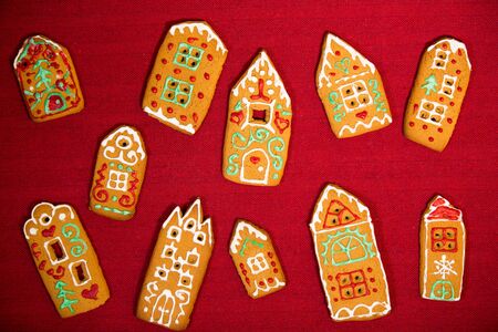 Christmas background. Red table cloth with town of cute gingerbread houses decorated with icing.の写真素材