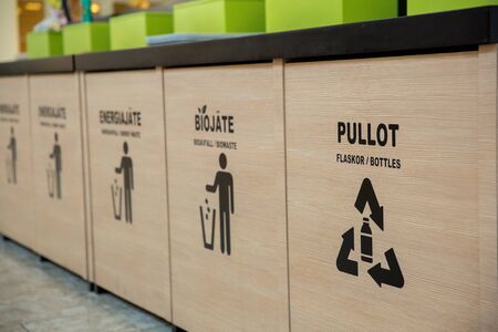 Trash bins in public area next to fast food restaurant, separating different kinds of garbage....
