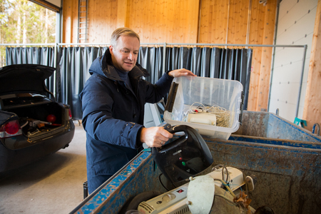 KIRKKONUMMI, Finland - OCT 04, 2019: Sorting station HSY - center for sorting, safe disposal and recycling of garbage. A man putting old appliances into dumpster.のeditorial素材