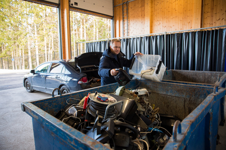 KIRKKONUMMI, Finland - OCT 04, 2019: Sorting station HSY - center for sorting, safe disposal and recycling of garbage. A man putting old appliances into dumpster.のeditorial素材