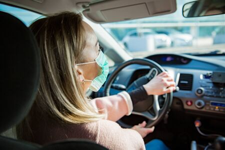 Woman in protective mask driving a car on road. Safe traveling.の写真素材