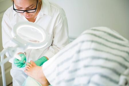 Woman sitting in chair, having foot treatment in spa salon.の写真素材