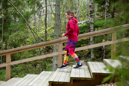 A sporty middle-aged woman training on a fitness ladder in a nature park in the forest