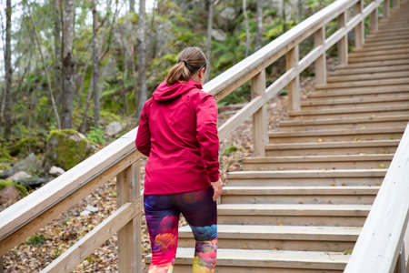 Athletic middle-aged woman running up the Fitness Stairs in a natural park in the woodsの写真素材