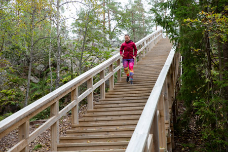 Athletic middle-aged woman running up the Fitness Stairs in a natural park in the woodsの写真素材