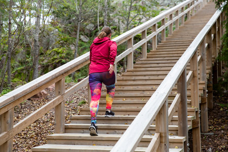 Athletic middle-aged woman running up the Fitness Stairs in a natural park in the woodsの写真素材