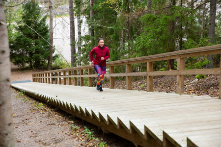 Athletic middle-aged woman running up the Fitness Stairs in a natural park in the woodsの写真素材