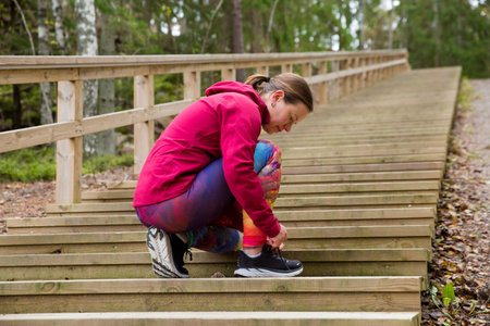 A sporty middle-aged woman is ready for a workout on the fitness stairs in a natural park in the forestの写真素材