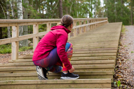A sporty middle-aged woman is ready for a workout on the fitness stairs in a natural park in the forestの写真素材