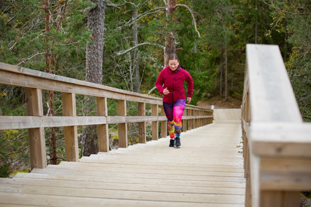 Athletic middle-aged woman running up the Fitness Stairs in a natural park in the woodsの写真素材