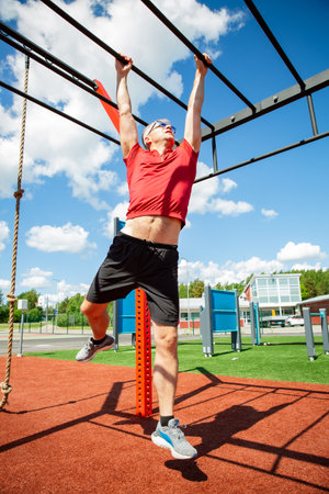Active 50-year-old man uses monkey bars at an outdoor fitness station, training grip and upper body in a dynamic strength workouの写真素材