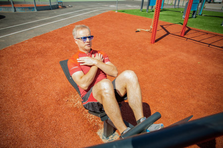 Man training on an adjustable abdominal bench. Targets core and abs. Outdoor workout improves core strength, balance, and physical control.の写真素材