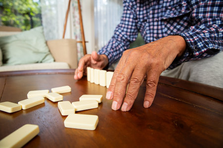 Close-up of elderly fathers hands placing dominoes on the table during a quiet game with his adult son - a tender moment of age and connection.の写真素材