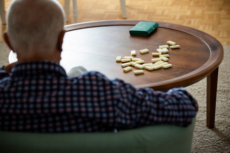 Domino game in focus, lonely elderly man blurred. A quiet image of solitude, aging, and the slowness...
