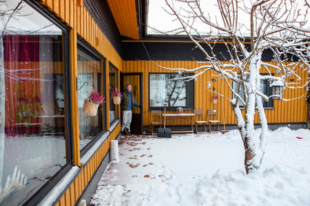Middle-aged man stepping out into snowy yard to perform winter chores, outdoor lifestyle and seasonal activity, cold weather and active routine.の写真素材