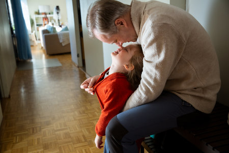 Father helping toddler get dressed in overall at hallway, child learning to put on clothes before going outside in cold season.の写真素材