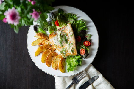 Delicious fried swordfish steak with roasted potato wedges, fresh greens, and creamy sauce. Healthy...
