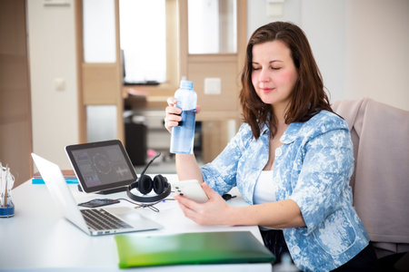 Business woman using mobile health app to track hydration in office. Digital wellness, workplace...