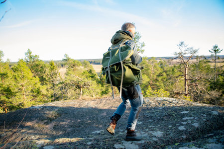 Male hiker taking photos with vintage camera on scenic cliff in Finland. Travel photography, adventure tourism and outdoor lifestyle concept.の写真素材