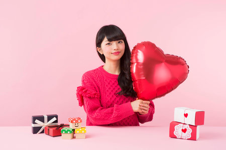 A woman holding a heart shaped balloonの写真素材