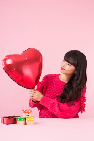 A woman holding a heart shaped balloonの写真素材