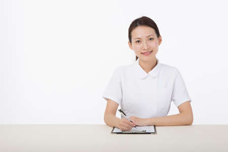 a young woman in white who fills out a questionnaire on the tableの写真素材