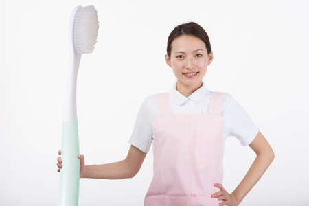 a young woman in white with a big toothbrush in her handの写真素材