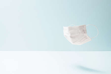 a white mask floating on a light blue backgroundの写真素材