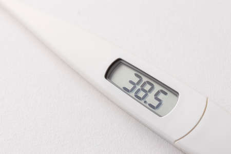 Digital thermometer that displays a high temperature of 38.5 degrees above a white backgroundの写真素材