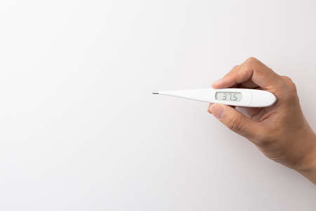 a hand with a digital thermometer that displays a slight fever of 37.5 degrees on a white backgroundの写真素材