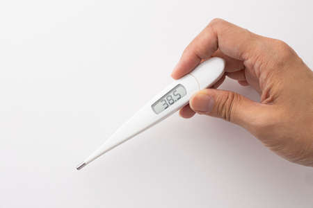 Digital thermometer that displays a high temperature of 38.5 degrees above a white backgroundの写真素材