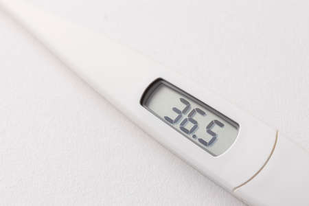 Digital thermometer that displays a flat temperature of 36.5 degrees above a white backgroundの写真素材