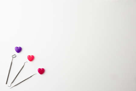 Dental instruments and colorful heart-shaped capsules placed on a white background