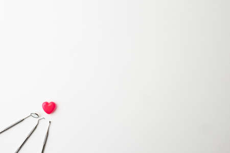 dental instruments and pink heart-shaped capsules placed on a white backgroundの写真素材