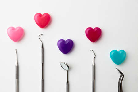 Dental instruments and colorful heart-shaped capsules placed on a white backgroundの写真素材
