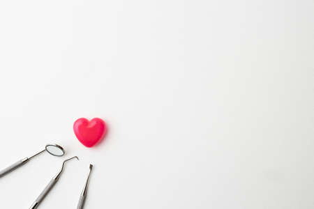 dental instruments and pink heart-shaped capsules placed on a white backgroundの写真素材