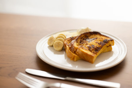 French toast with banana and butter on wood table. Selective focus.の写真素材