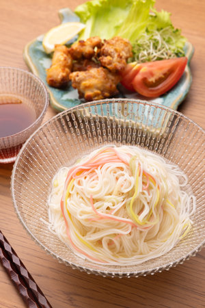 Japanese thin wheat noodles with fried chicken on a wooden tableの写真素材